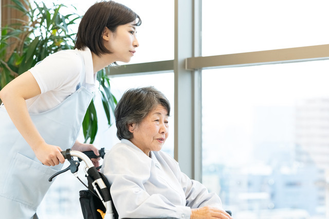 車椅子に乗る高齢者と介護士のイメージ